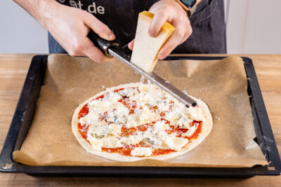 Parmesan über Pizza streuen.