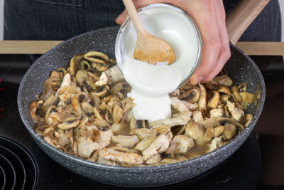 Saure Sahne zum Putengeschnetzelten mit Chamoignons geben