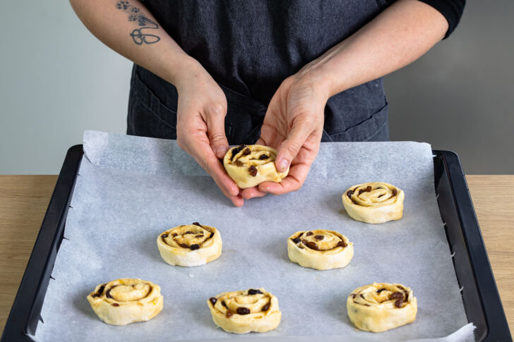 Rohe Rosinenschnecken auf Backblech verteilen
