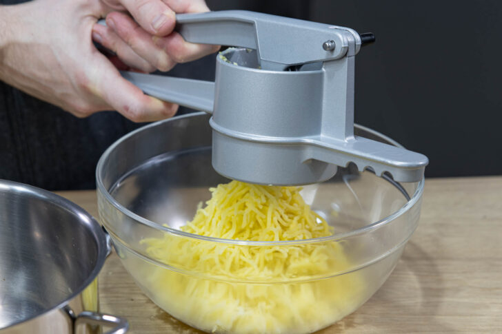 Kartoffeln durch die Kartoffelpresse drücken