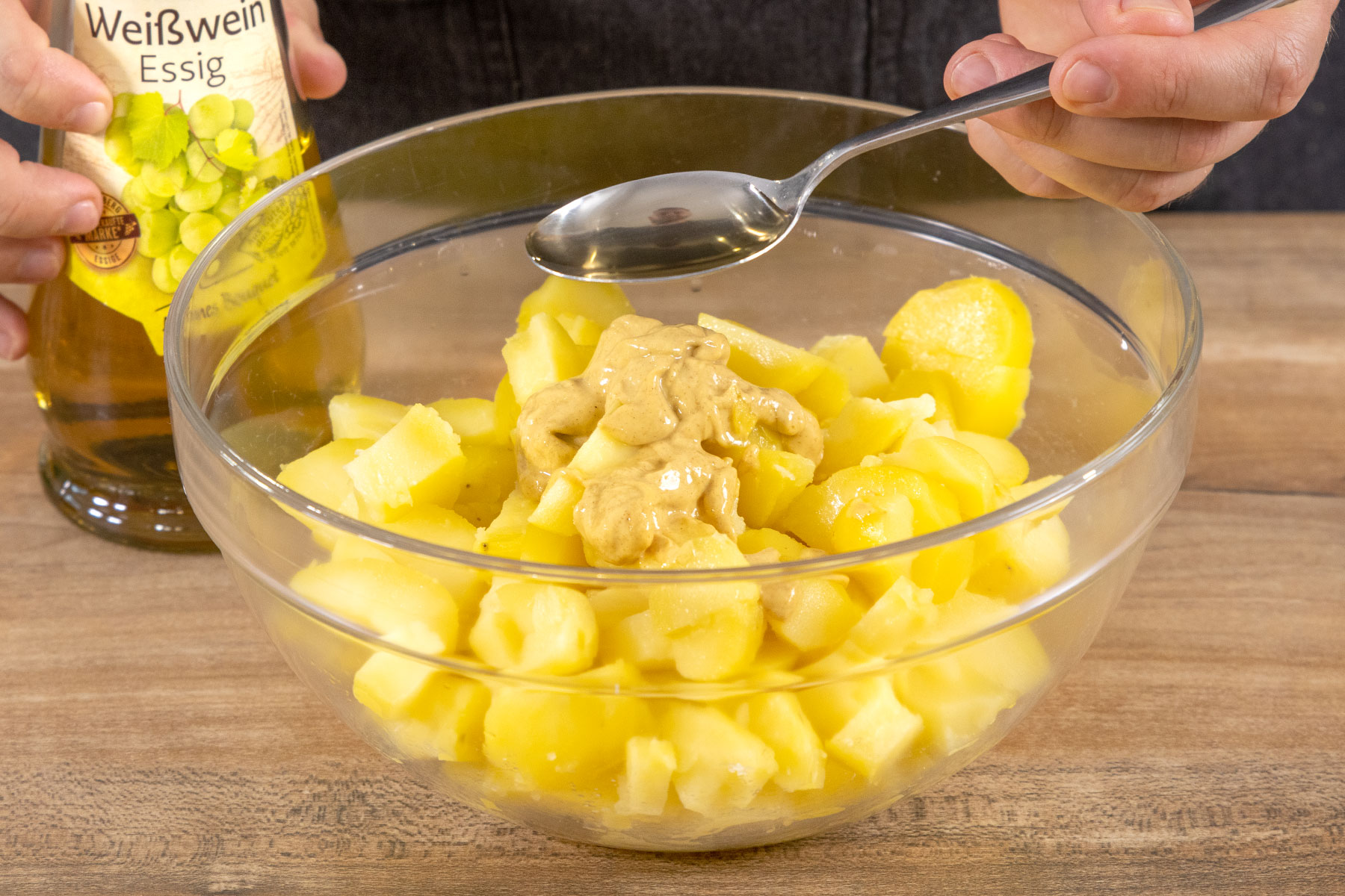 Essig zu dem Kartoffelsalat geben