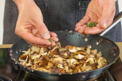 Salbei zu den Shiitake-Pilzen geben
