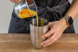 Orangensaft in Shaker geben