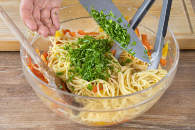 Gehackte Petersilie zum Spaghettisalat geben