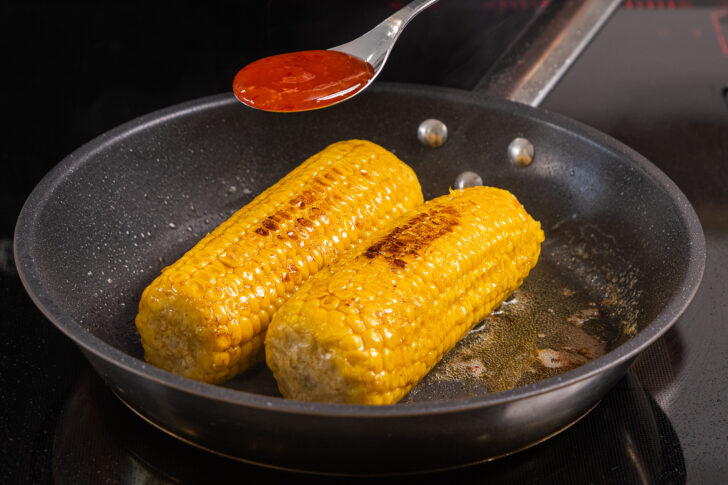 Maiskolben anbraten und Chili-Sauce darüber geben