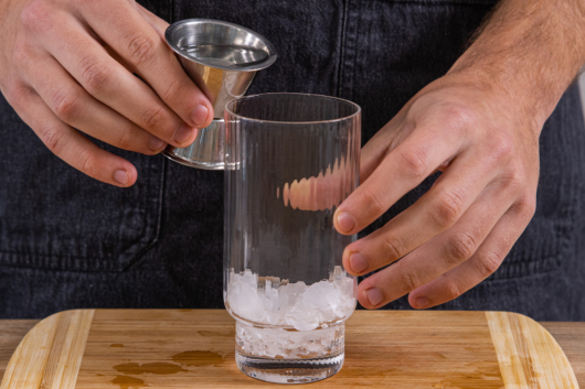 weißen Tequila in das Glas mit Eis geben
