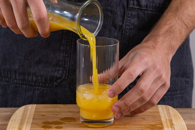 Das Glas mit Orangensaft auffüllen