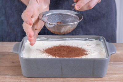Kakao-Staub auf das Tiramisu streuen
