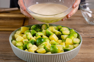 Soße über Kartoffeln und Rosenkohl gießen