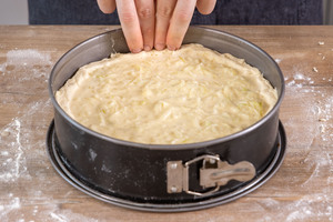 Teigrand des Zwiebelkuchens mit den Fingern runter drücken