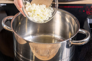 Zwiebelwürfel in einen Topf geben