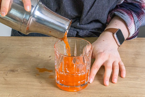 Aperol Sour Cocktail in ein Glas gießen