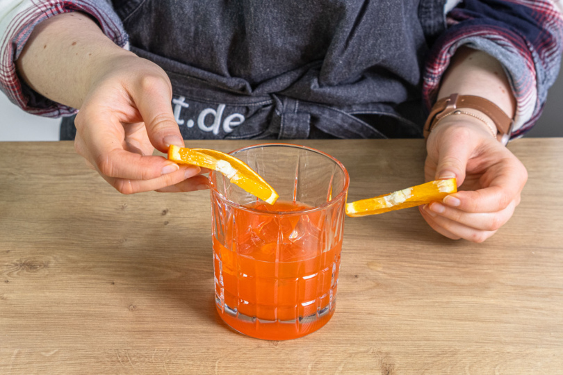 Orangenscheiben zum Aperol Sour Cocktail geben