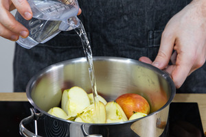 Äpfel und Wasser in Topf geben