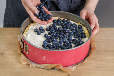 Blaubeeren auf den Quarkkuchen geben