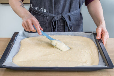 Teig für Buttermilchkuchen mit Mandeln verstreichen