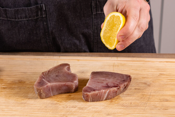 Zitronensaft über Thunfischsteaks geben