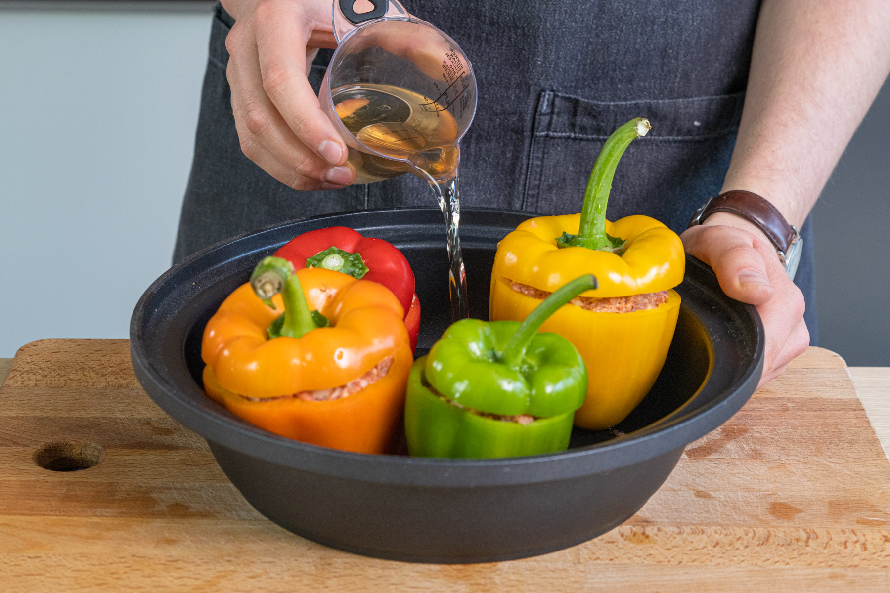 Gemüsebrühe zu den gefüllten Paprika gießen