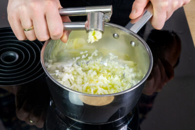 Knoblauch zu der Zwiebel pressen