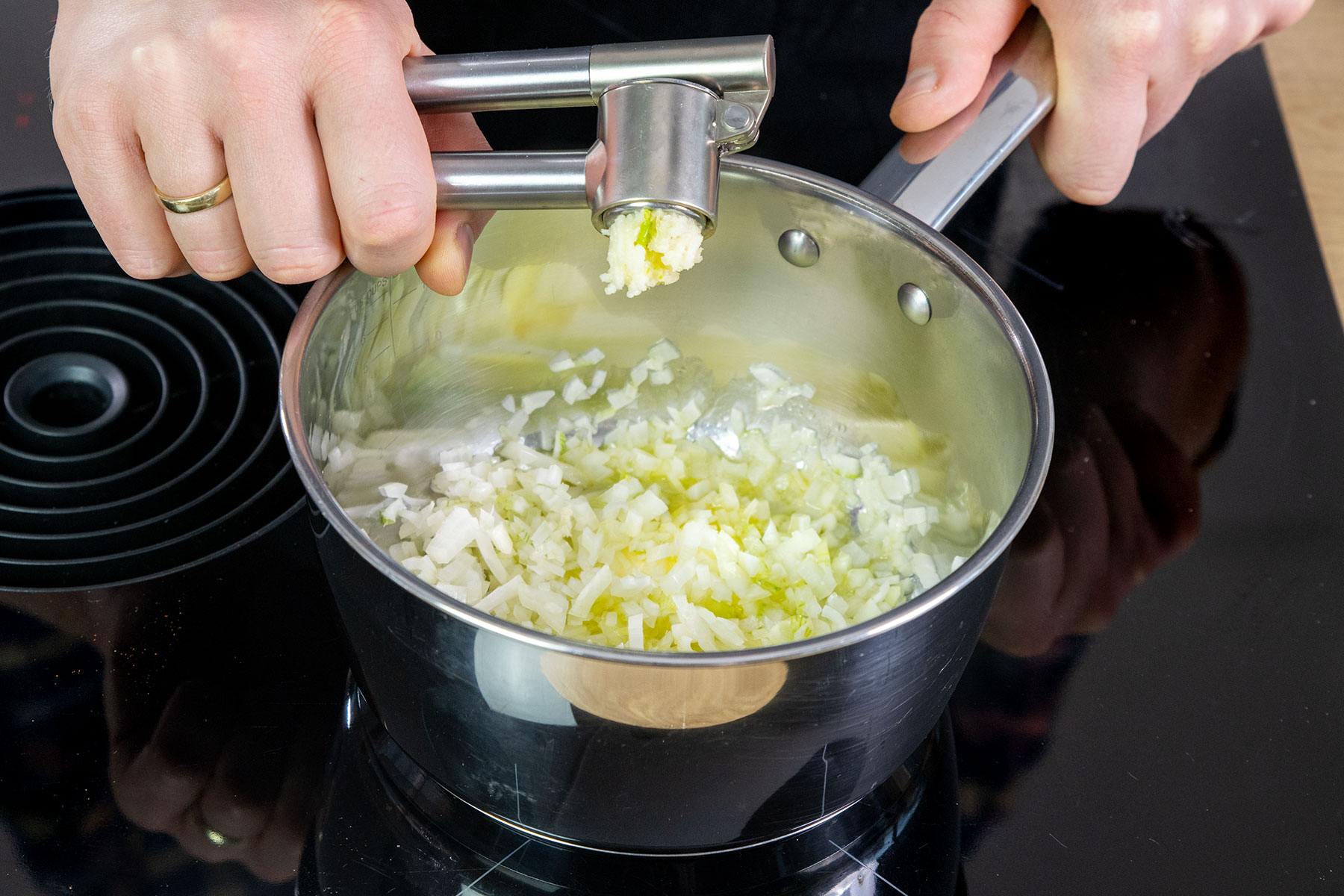 Knoblauch zu der Zwiebel pressen