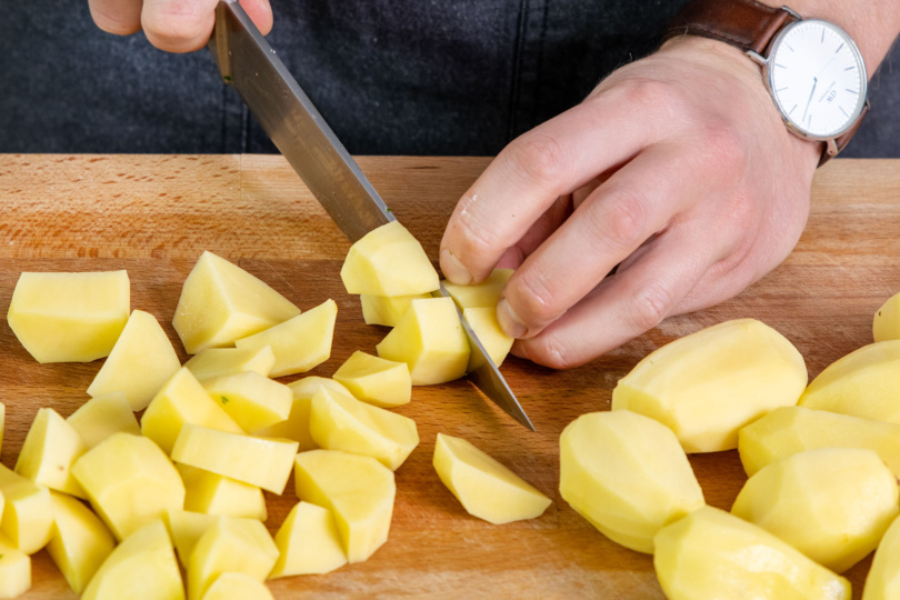 Kartoffeln als Beilage zu dem gefüllten Schweinebauch in mundgerechte Stücke schneiden