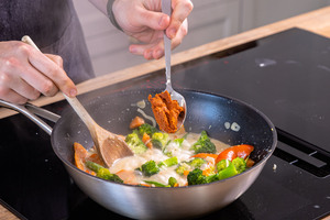 rote Currypaste zu Gemüsecurry mit Kokosmilch geben