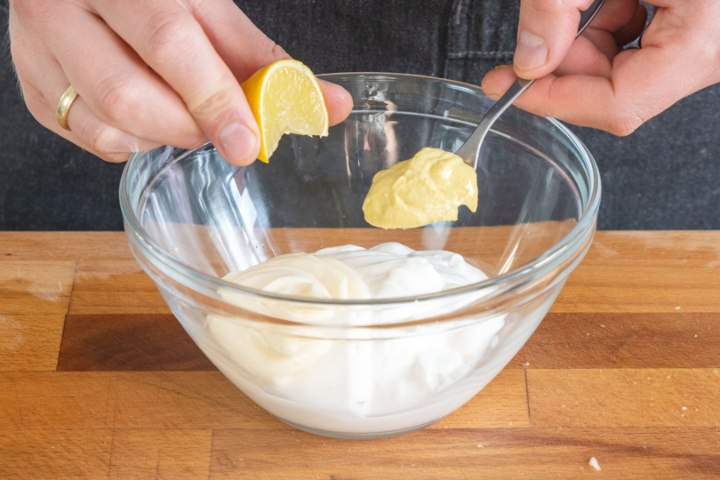 Zitronensaft uns Senf zur sauren Sahne und Mayonnaise in die Schüssel geben