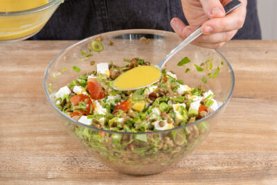 Dressing über den Linsensalat mit Feta geben
