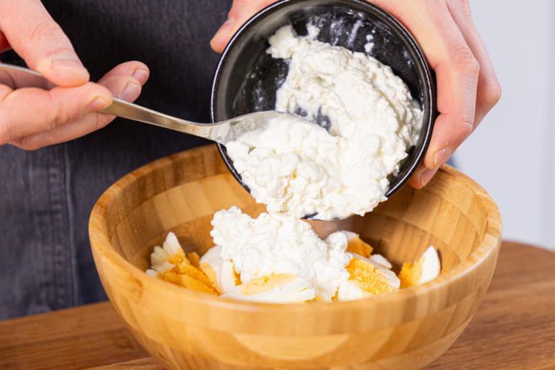 Hüttenkäse zu den Eier geben