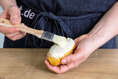 Mini Eclairs mit weißer Schokolade bestreichen