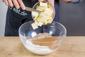 Butterstücke zu den Zutaten des Mürbeteigbodens geben