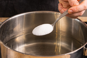 Salz in einen Topf mit Wasser geben