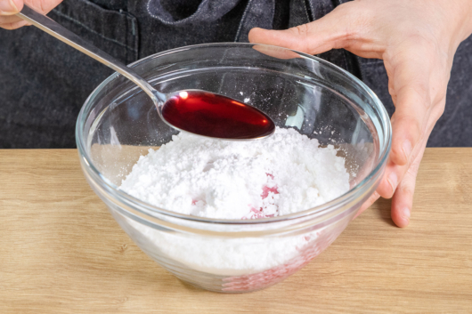 Kirschsaft zu dem Puderzucker geben