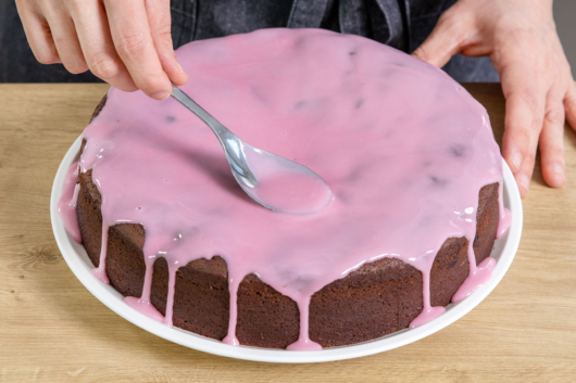 Glasur auf dem Rotweinkuchen verteilen