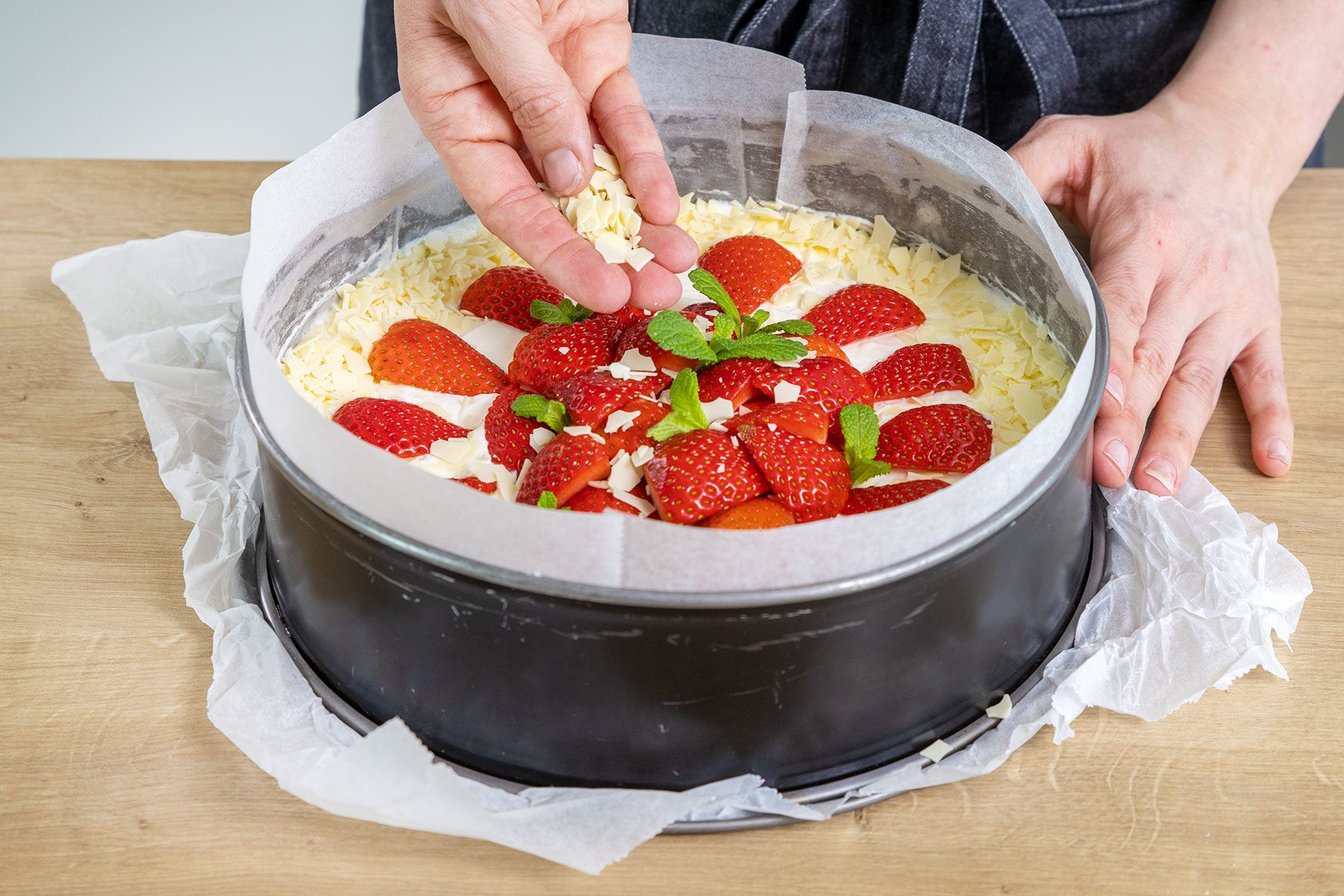 Schnelle Erdbeertorte ohne Backen mit Erdbeeren, Schokoraspeln und Minze dekorieren