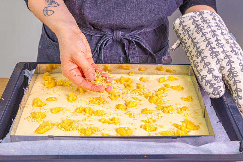 Streusel und Mandeln auf dem Schmandkuchen verteilen