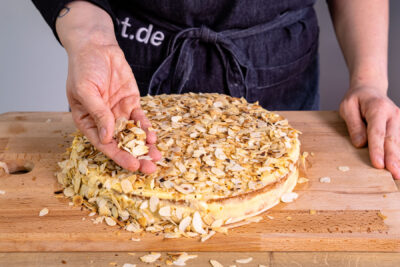 Schwedische Mandeltorte mit Mandeln bestreuen