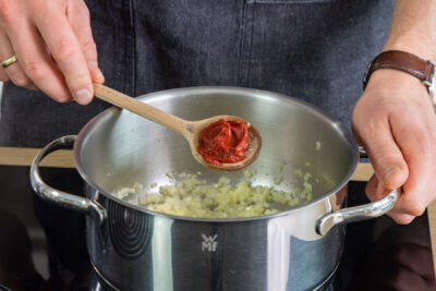 Tomatenmark zu den Zwiebeln geben