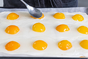 Den Guss auf den Spiegeleikuchen mit Quark verteilen