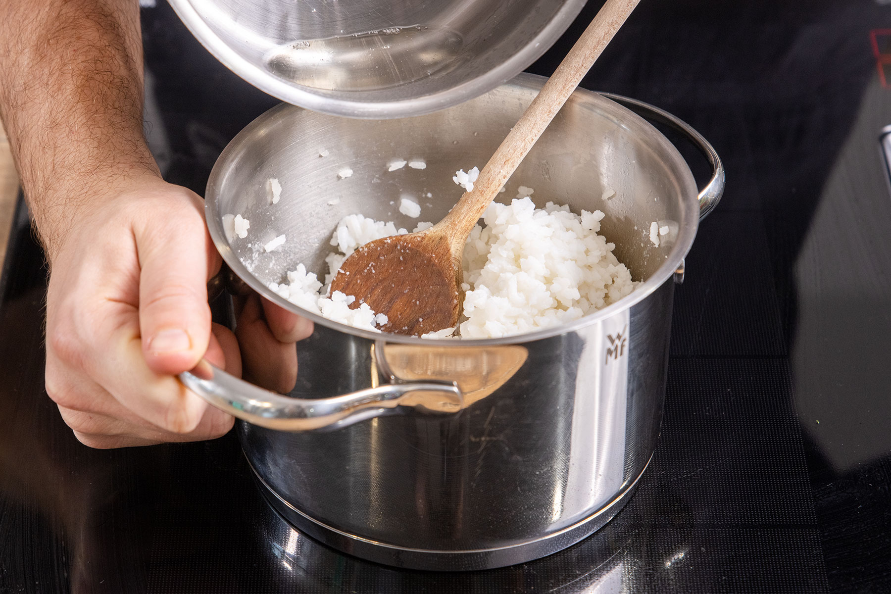 Reisessig-Mirin-Mischung zu dem gekochten Sushi-Reis geben