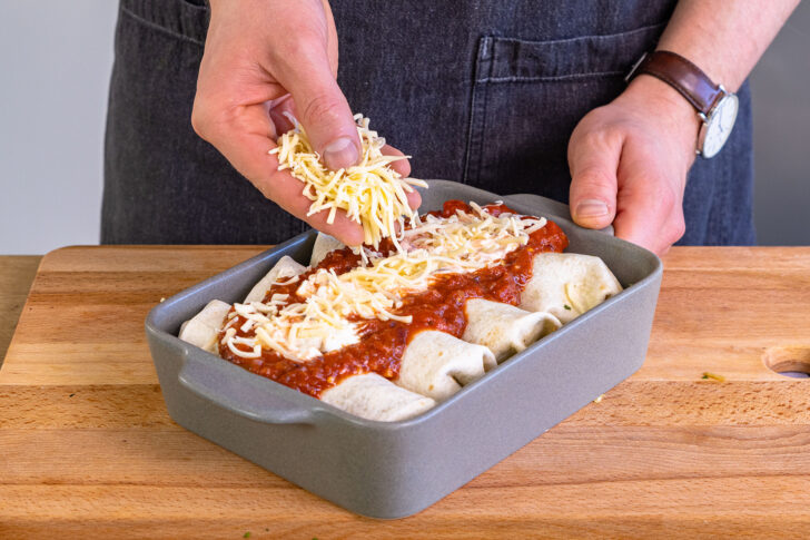 Schmand und Gouda auf Enchiladas geben