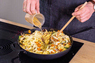Gemüsebrühe in vegetarische Spätzlepfanne gießen