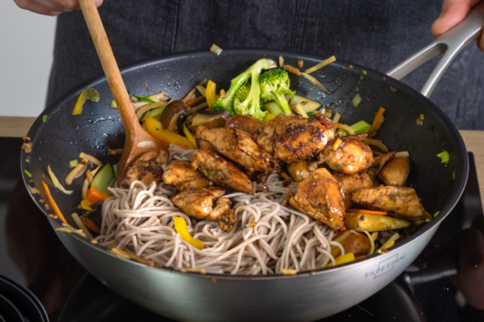 Asiatische Nudelpfanne mit Hähnchen und Gemüse in der Pfanne braten