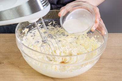 Sahne zur aufgeschlagenen Butter geben