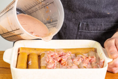 Sauce zum Cannelloni-Auflauf geben