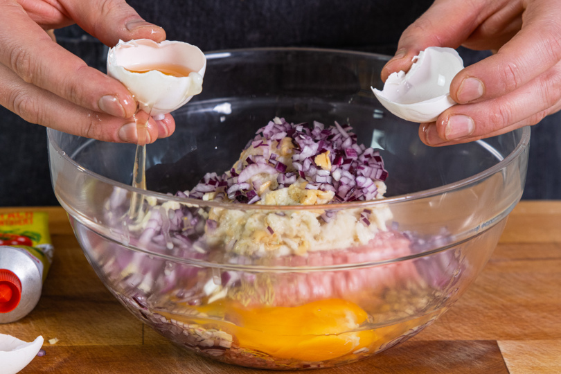 Eier in eine Schüssel mit Hackfleisch, Brötchen und Zwiebeln geben
