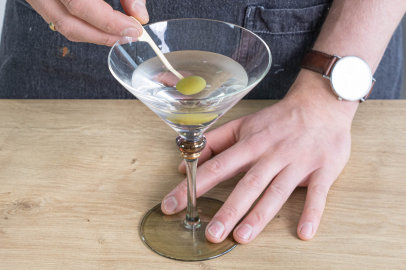 Dry Martini Cocktail mit Olive garnieren
