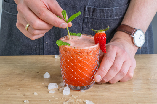 Erdbeer-Mojito Cocktail mit Minze dekorieren