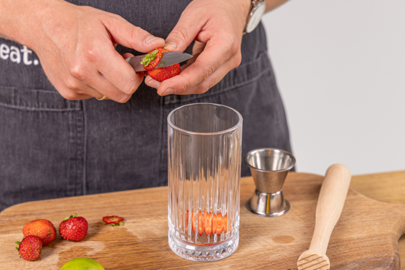 Erdbeeren schneiden und in Cocktailglas geben