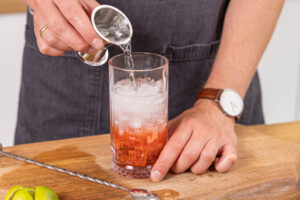 Rum und Sodawasser ins Glas geben